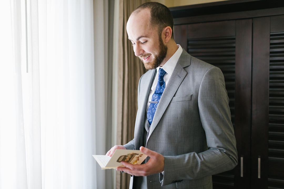 groom stands by window and reads a letter from his bride