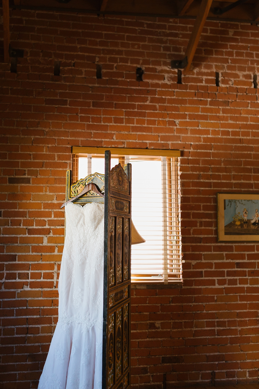 wedding gown hangs against brick wall at Carondelet House