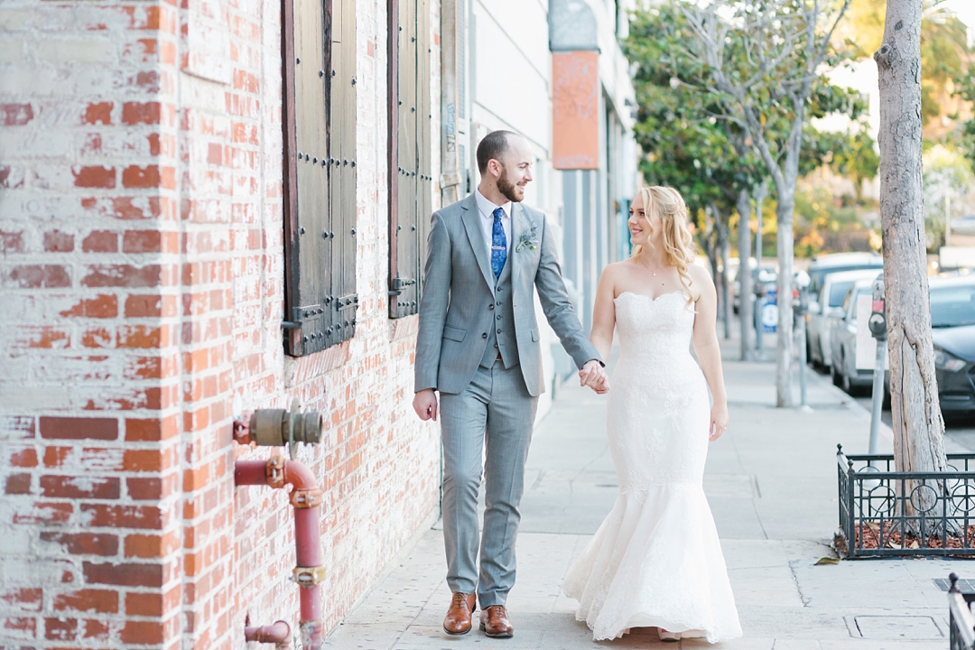 bride and groom walk holding hands in urban setting