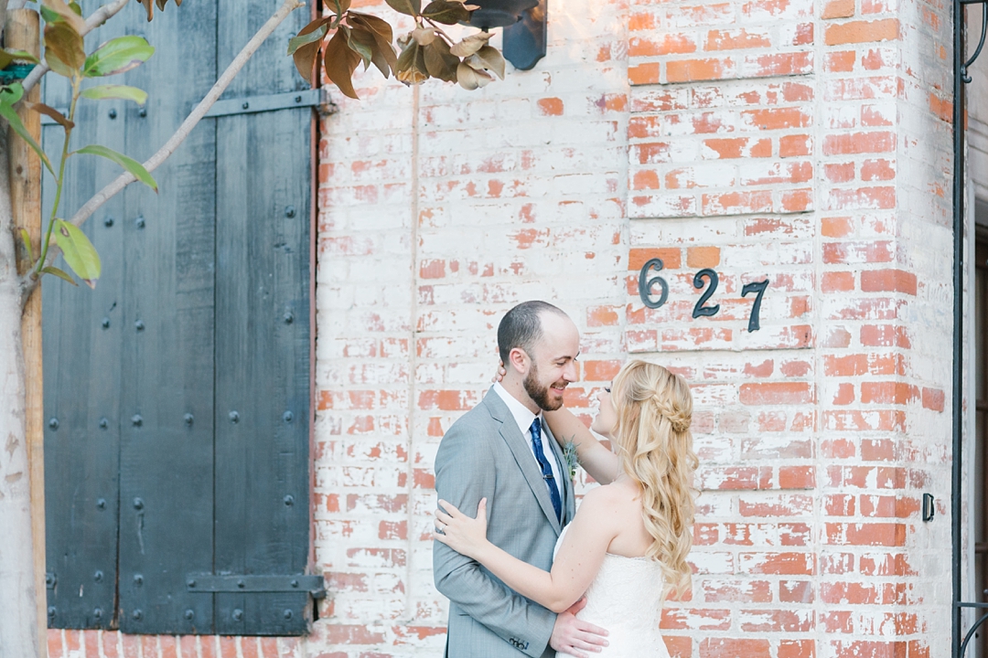 bride and groom in front of brick walled venue in los angeles