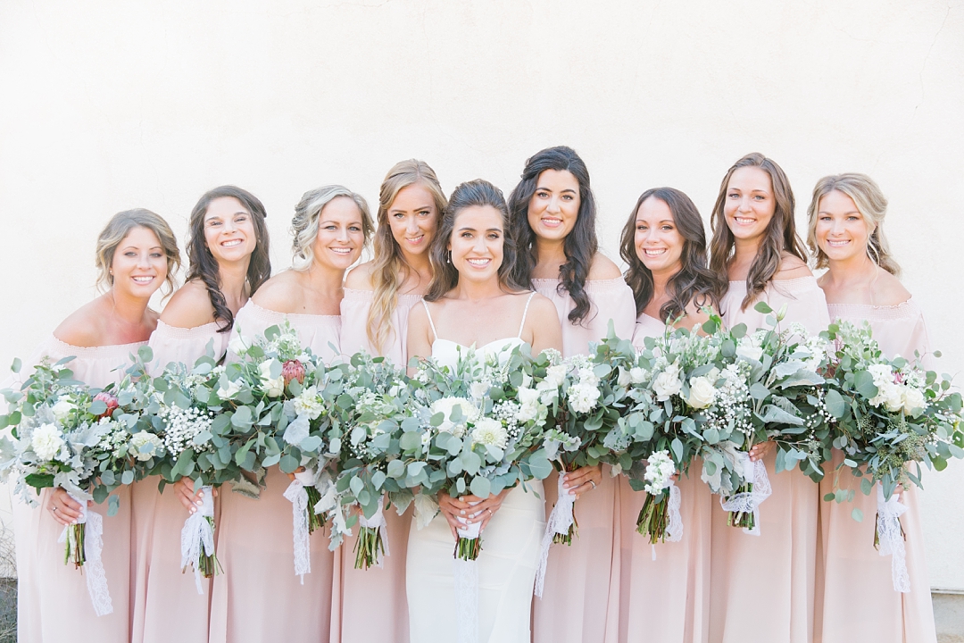 bridesmaids in soft pink dresses against white wall