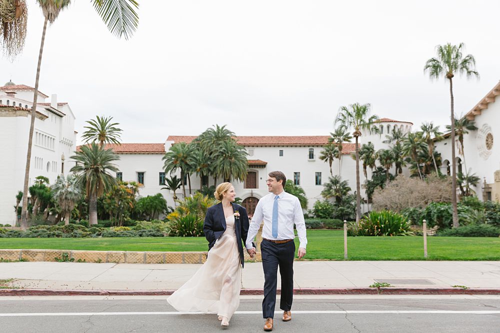 bride and groom cross street in front of the santa barbara courthouse where they eloped