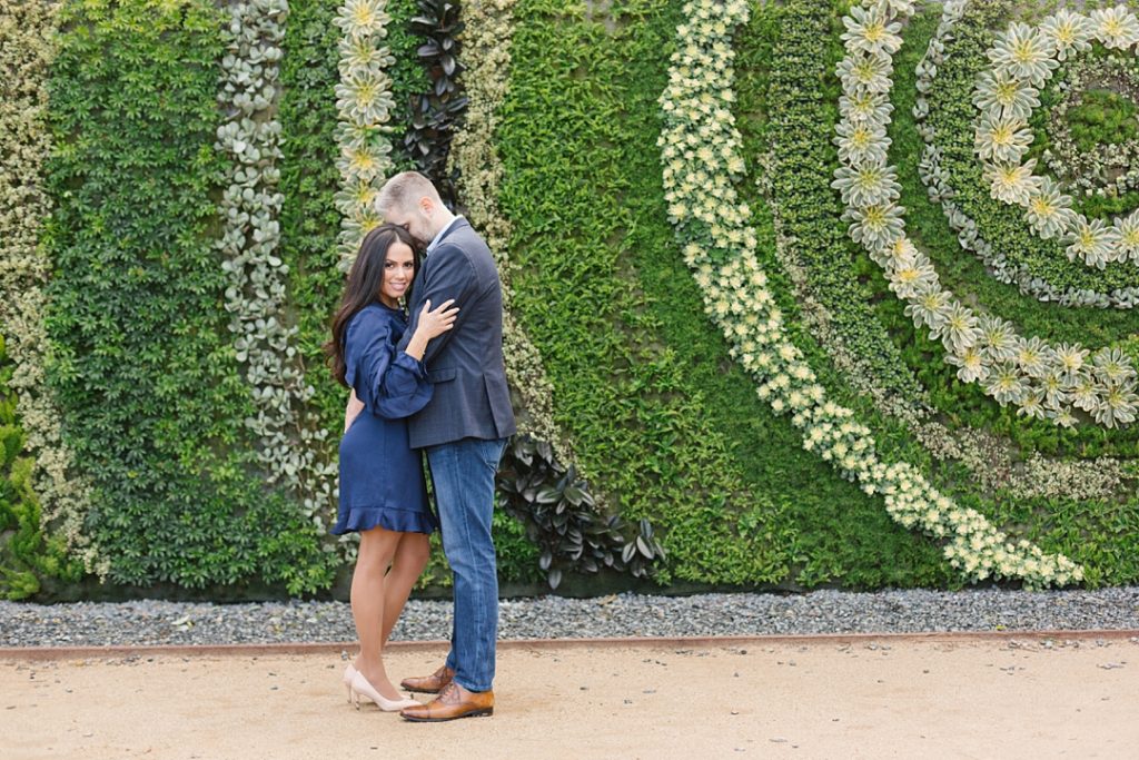 couple poses for engagement photos in front of living wall at south coast botanic garden