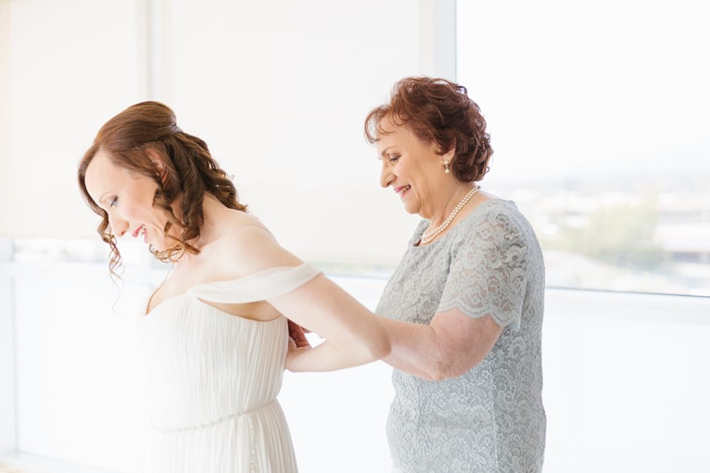 mother of the bride helps daughter into her BHLDN wedding gown