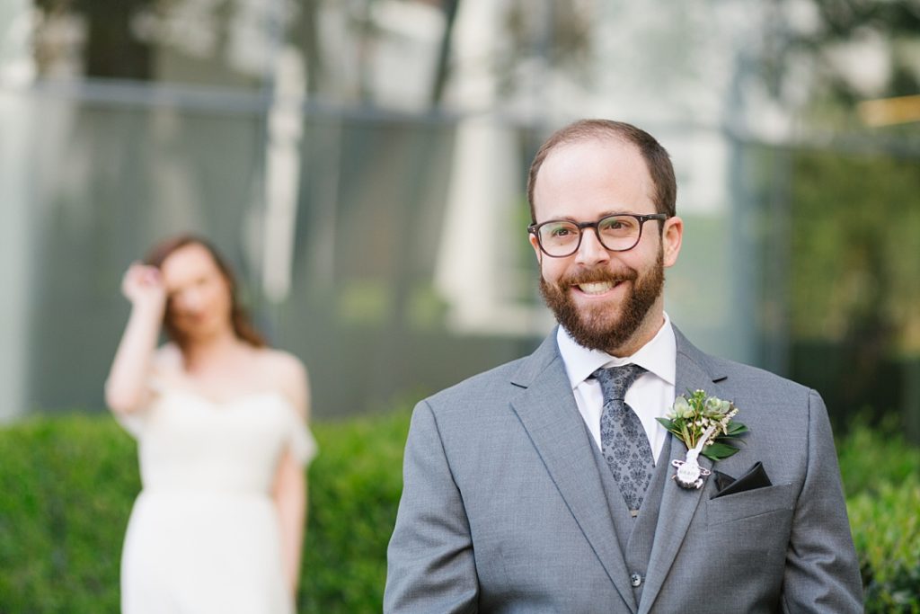 groom smiles as bride walks towards him for first look