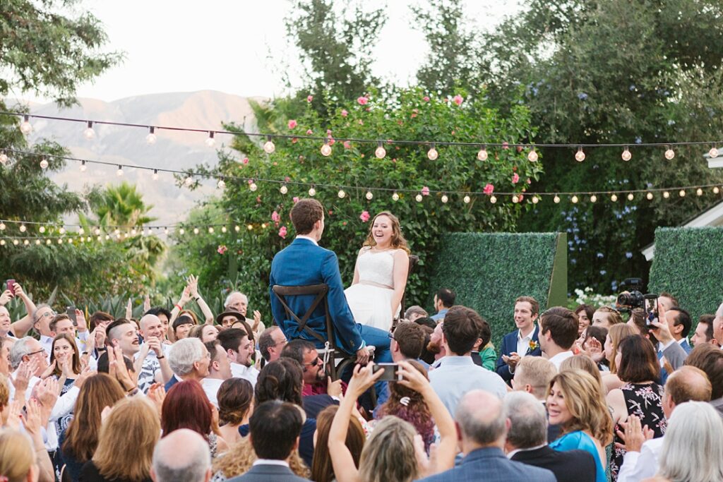bride and groom get lifted on chairs for hora at SoCal Jewish wedding