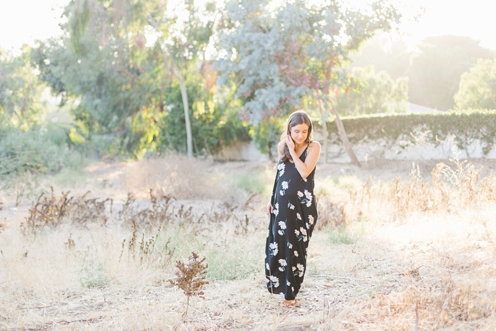 woman in black floral dress for maternity photos in Southern California