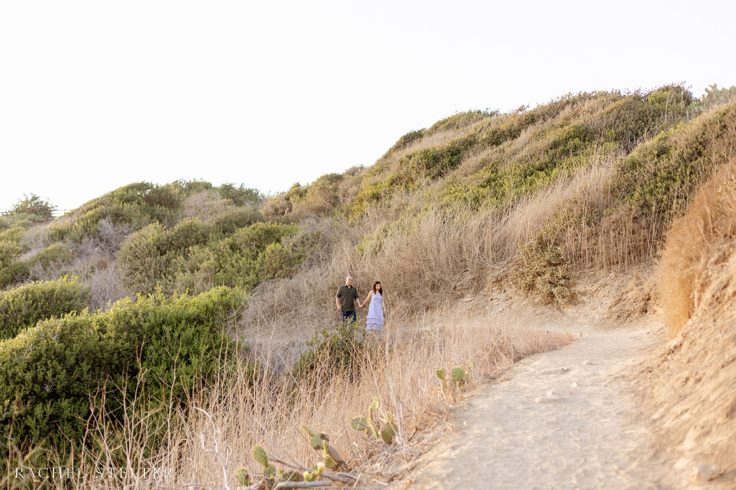 couple walks down winding path for their engagement photos at Abalone Cove 