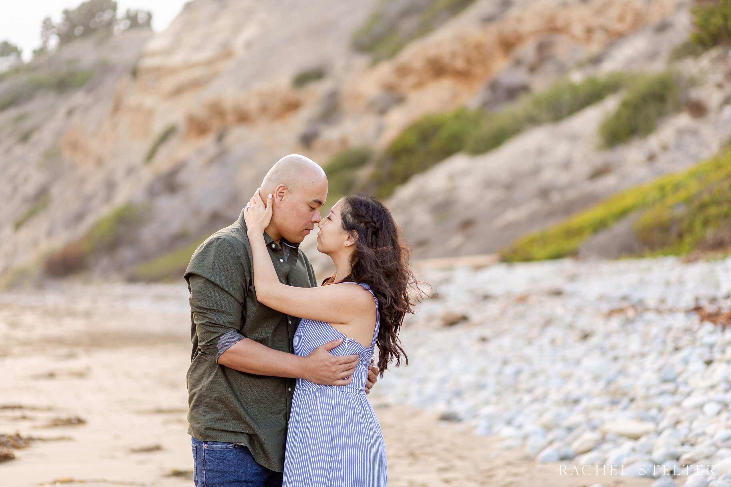 couple embraces with rocky beach in background for Palos Verdes engagement session