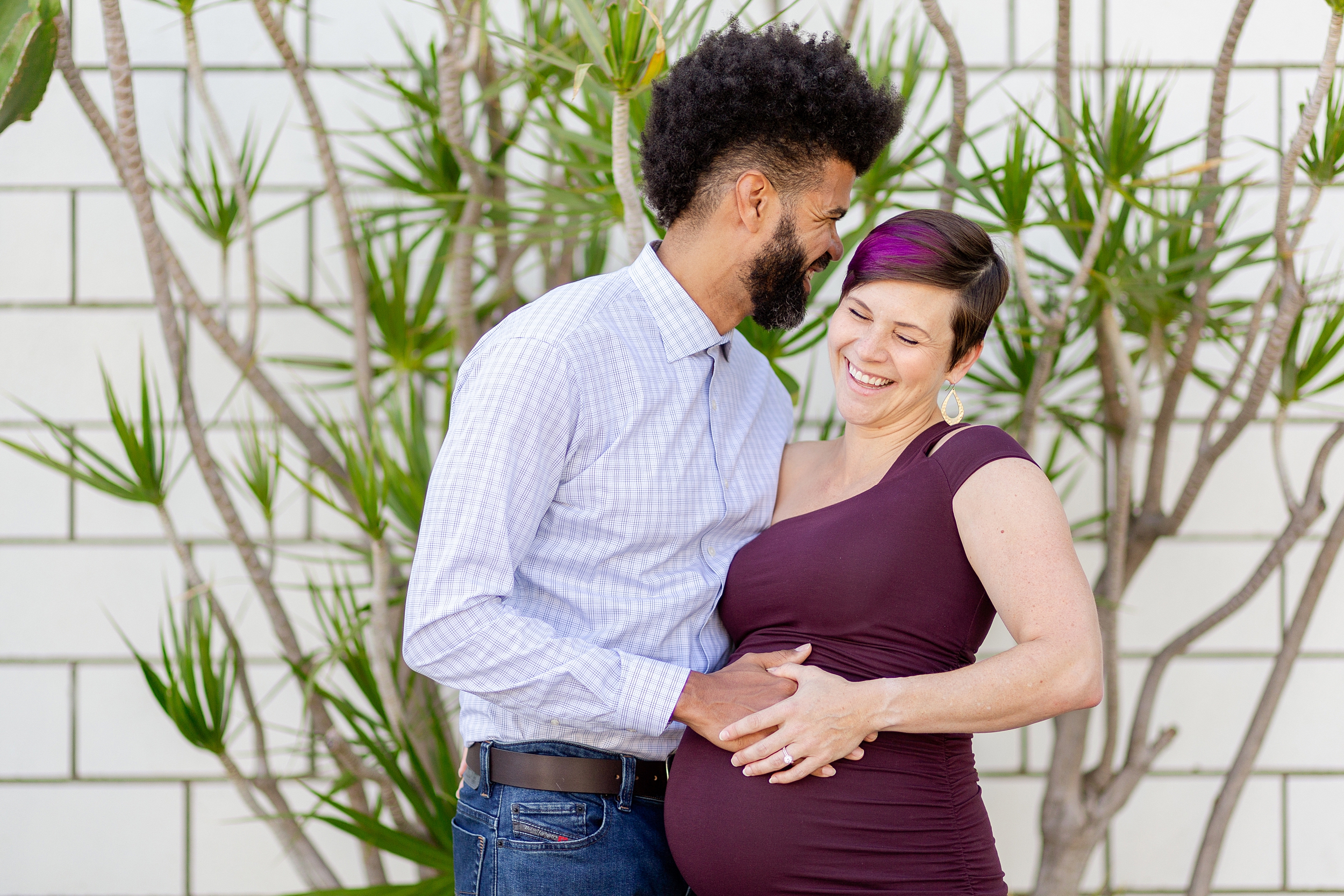 vibrant maternity photos in Los Angeles with couple laughing as they hold baby bump