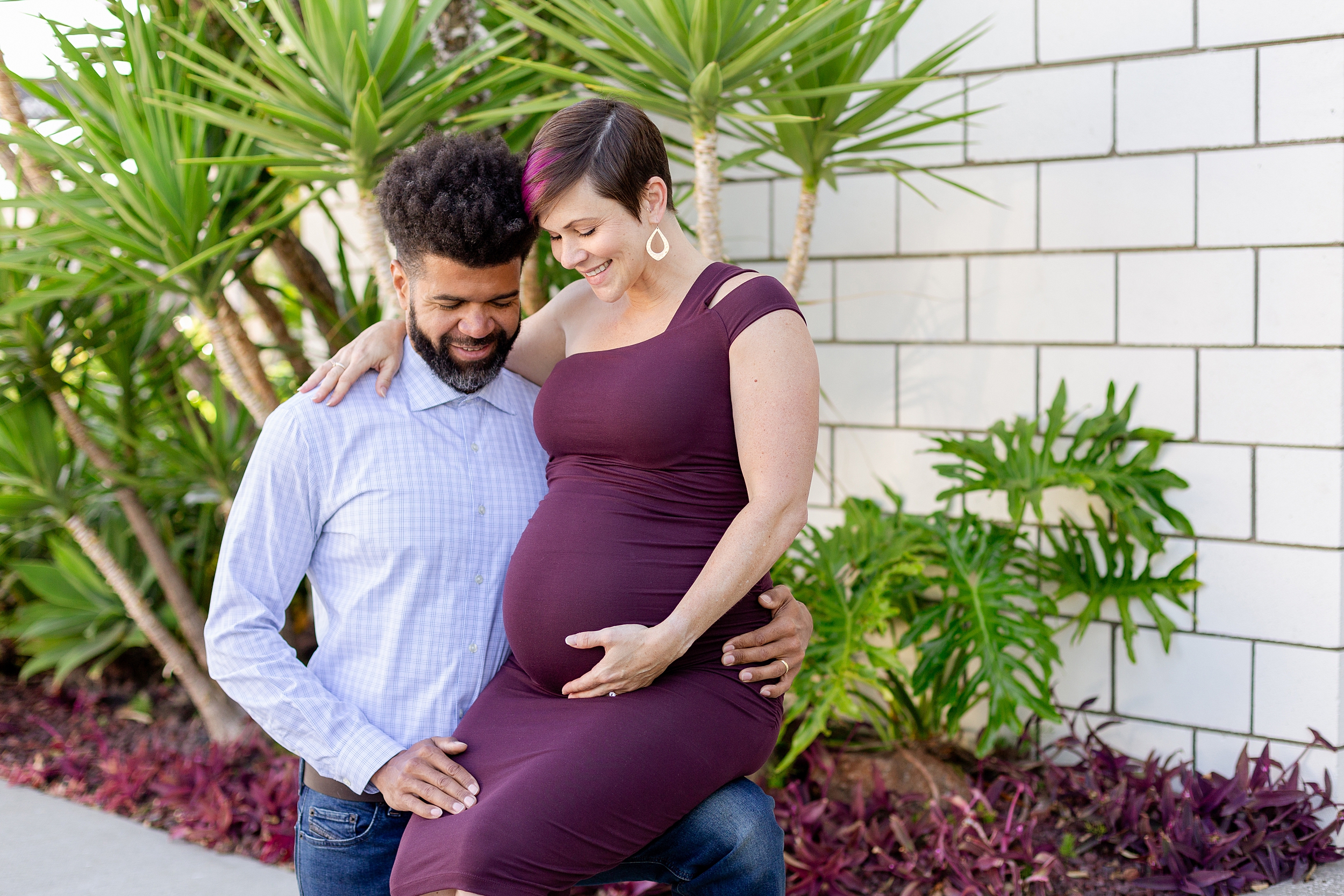 expecting parents smile at baby bump for outdoor maternity photos in Los Angeles