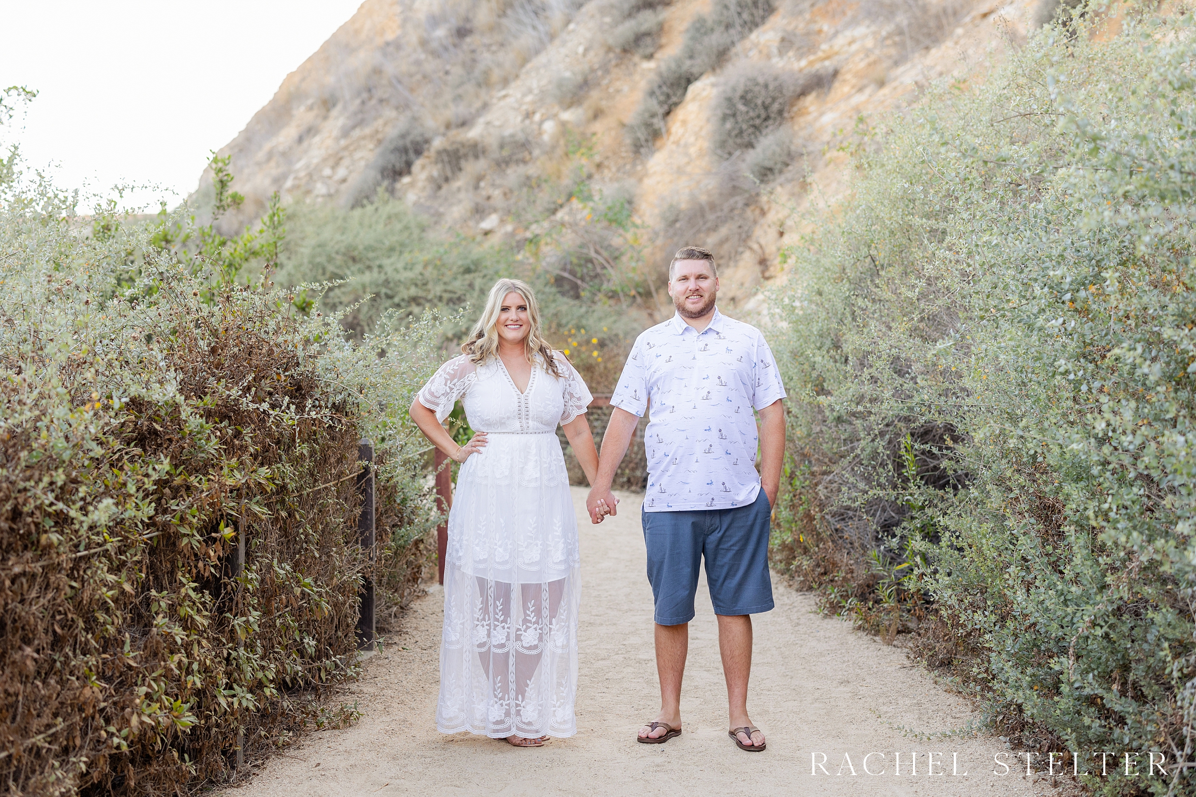 couple poses holding hands on Palos Verdes beach trail