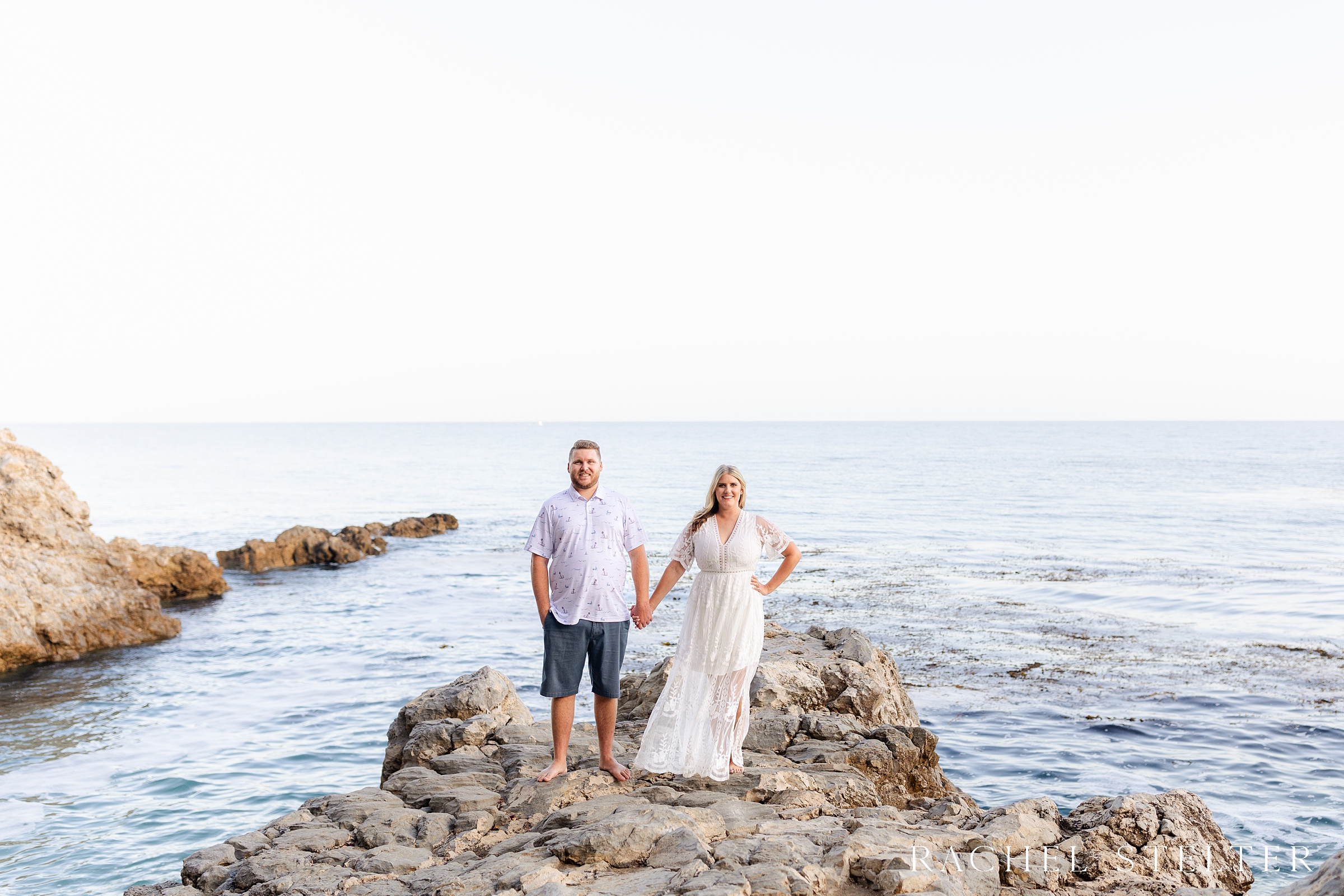 couple poses on rocks at Palos Verdes beach engagement