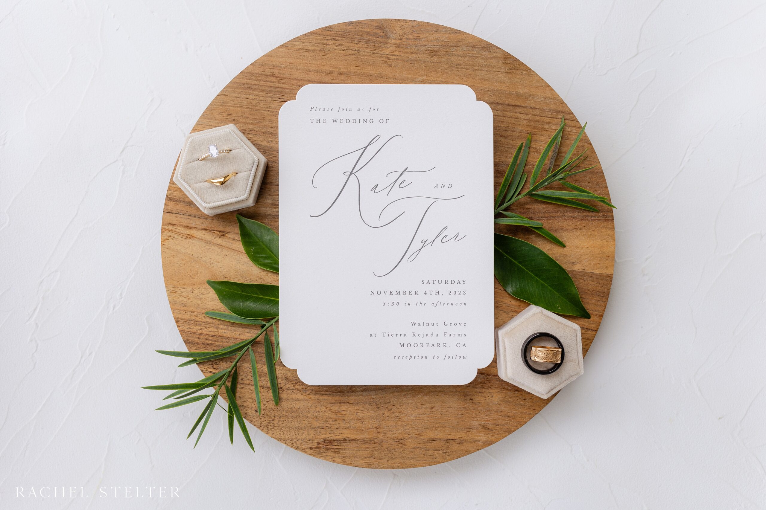 white wedding invitation photographed on circular wood platter